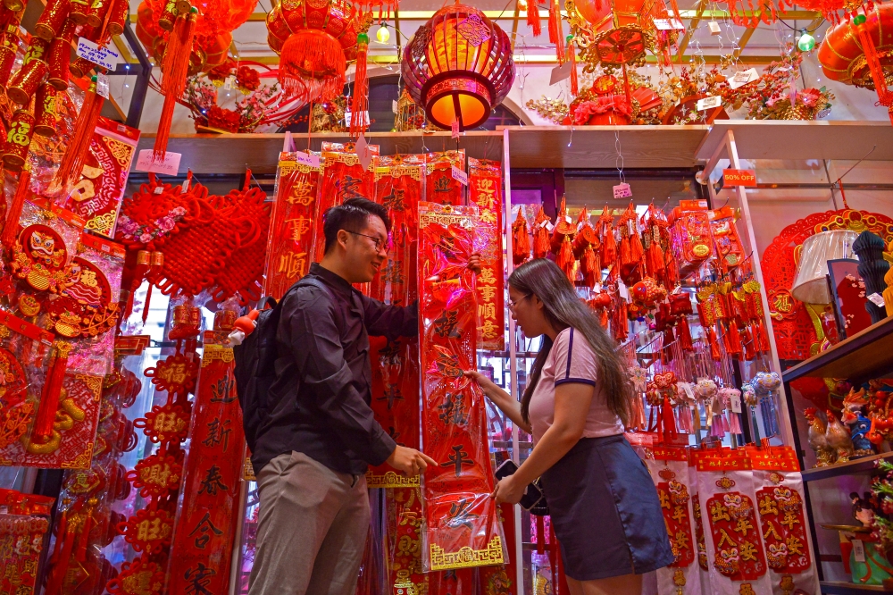 Pekerja swasta Tan Chin Seong, 31, dan isterinya Yow May Sim, 30, sibuk memilih barangan hiasan sebagai persiapan menyambut Tahun Baru Cina di sebuah kedai hiasan semasa tinjauan di Petaling Street, 13 Februari 2026. — Gambar Bernama 